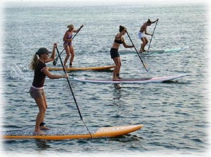 Women paddling stand-up boards in teambuilding exercise