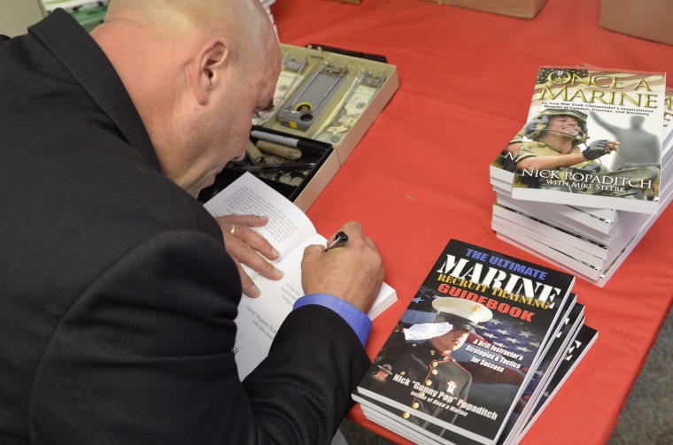Photo: Retired U.S. Marine Corps Gunnery Sergeant Nick Popaditch signing a copy of his memoir “Once a Marine."