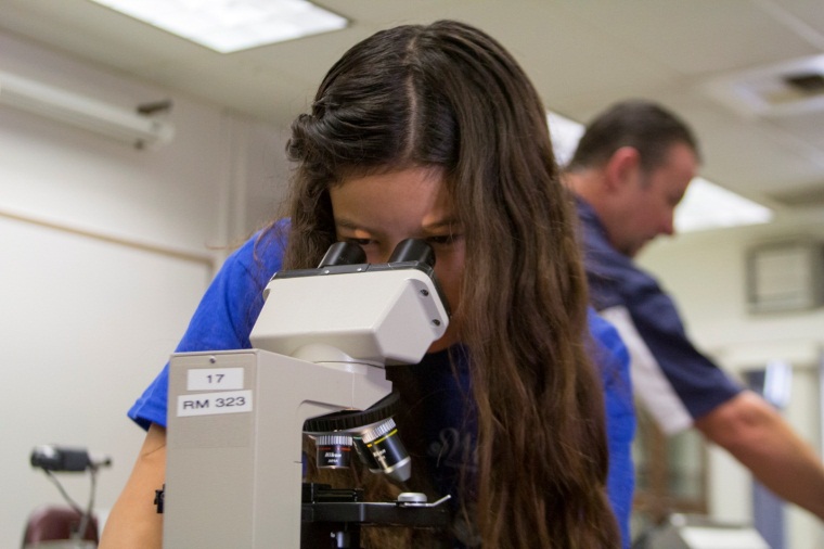 6th Grader Bibi Jimenez looks through microscope in College for Kids class