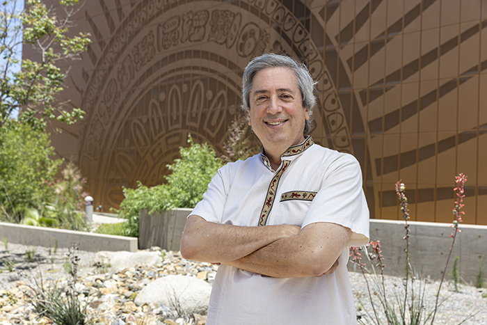 SWC Mariachi Professor, Jeffrey Nevin smiling in front of the sun mural on the SWC Performing Arts Center.