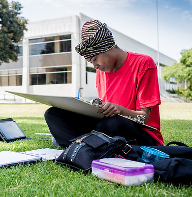 Student drawing and sitting on the grass