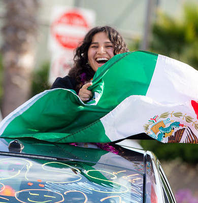 Student holding up Mexican flag during the Commencement Parade