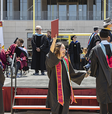Southwestern College graduate celebrating walking off stage with diploma in hand.