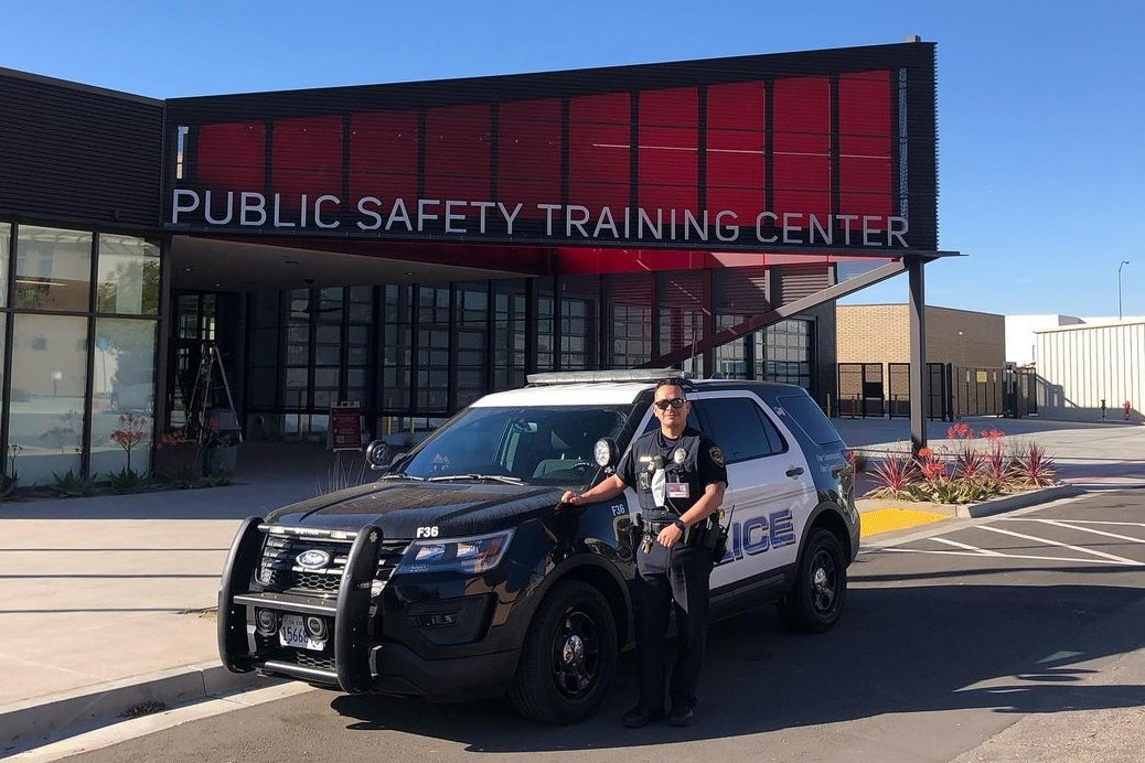 Officer Felix standing next to cruiser in front of the Public Safety Training Center