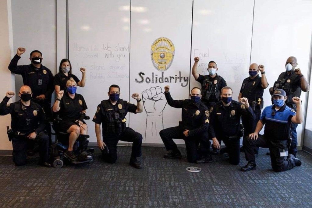 College police officers with their fists raised in solidarity