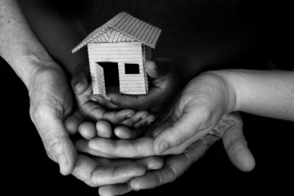 a black and white photo of a group of hands holding a small wooden house a black and white photo of a group of hands holding a small wooden house