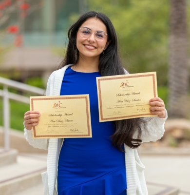 Photo of student holding scholarship certificates
